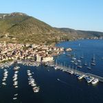 Yachts anchored in Komiža harbour with town and coastline of Vis island in the background